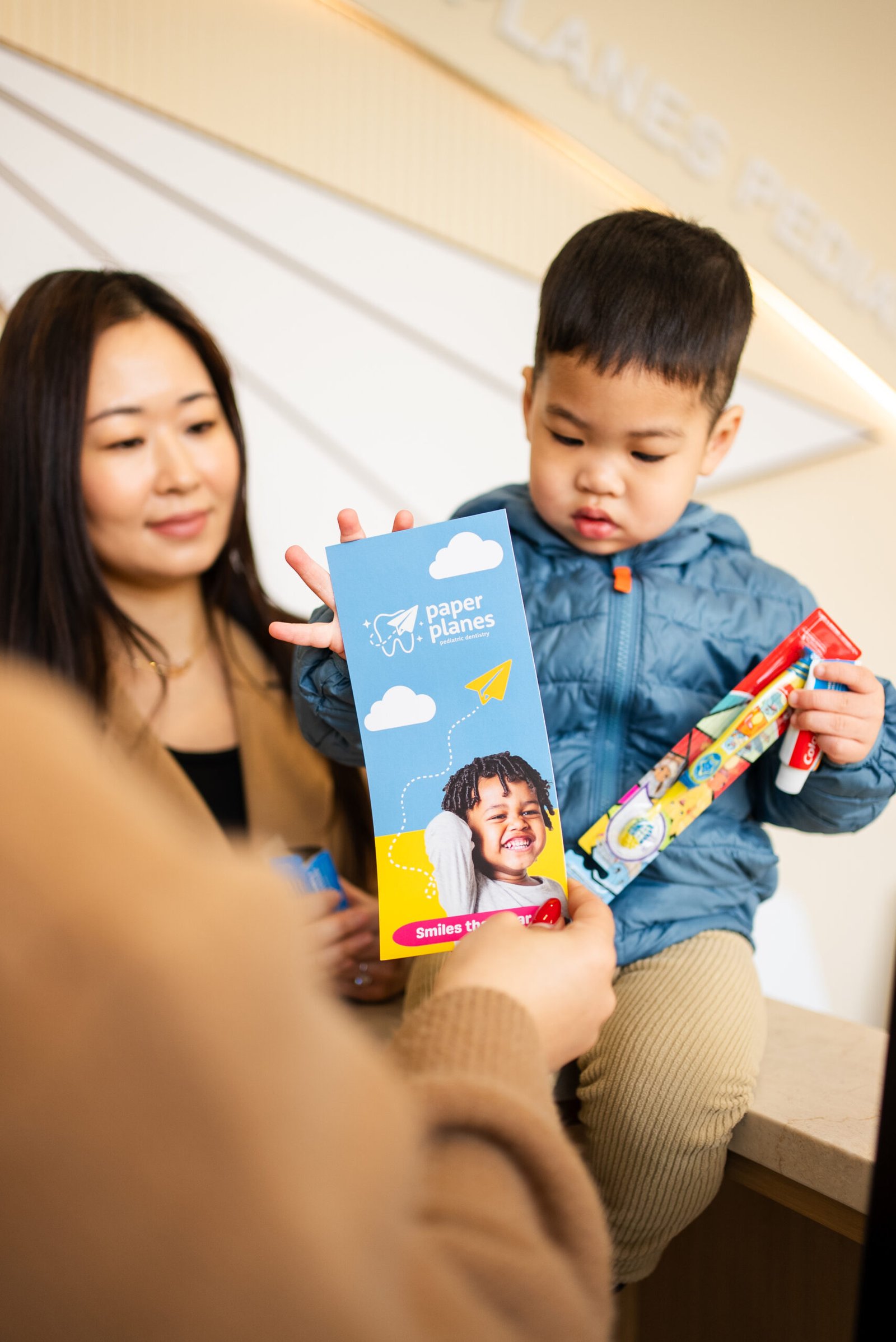 Mother sitting with child reading colorful book together in waiting area of pediatric dental clinic space.