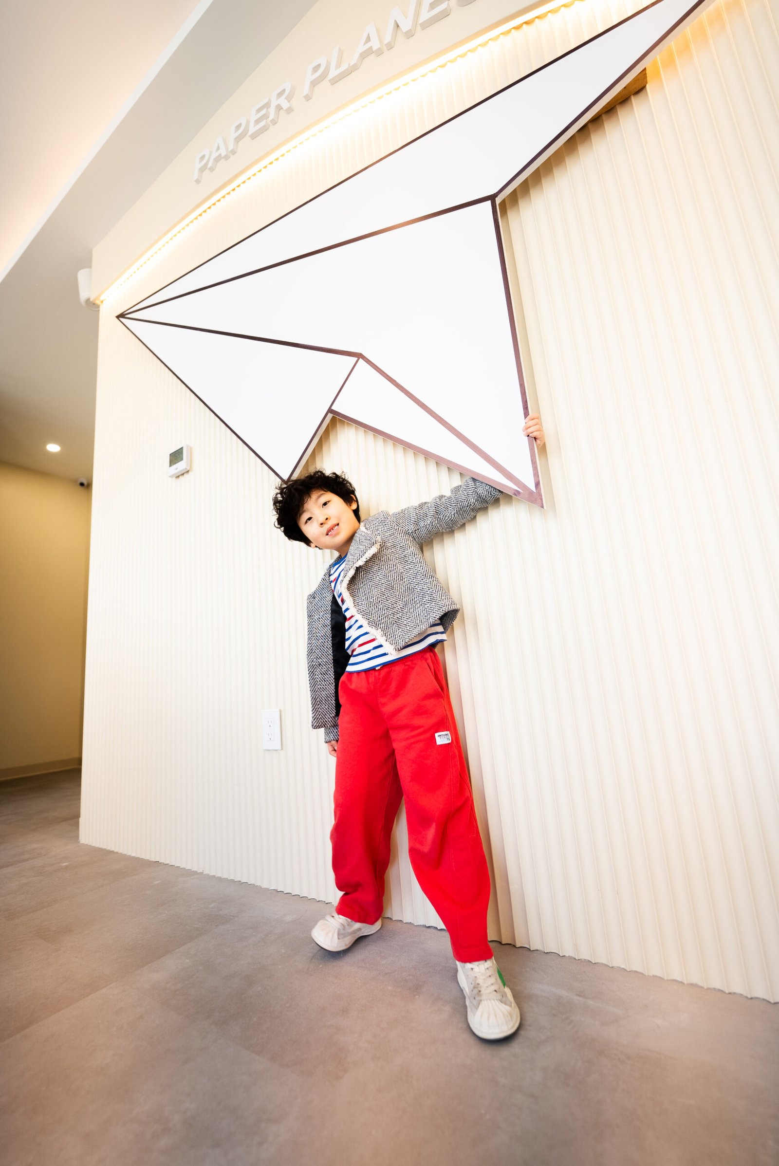 A Child holding overhead hanging structure, interacting with playful design element inside pediatric dental clinic environment.