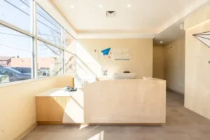 Reception desk area with large windows and natural light, showing entrance of pediatric dental clinic space.
